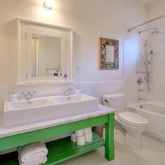 a bathroom with green and white fixtures, toilet, sink, shower stall and tub