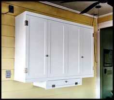 a white cabinet hanging from the side of a wall