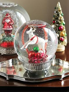 two snow globes on a table with christmas decorations