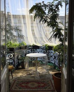 an open door leading to a balcony with potted plants on the other side and a small table in the middle