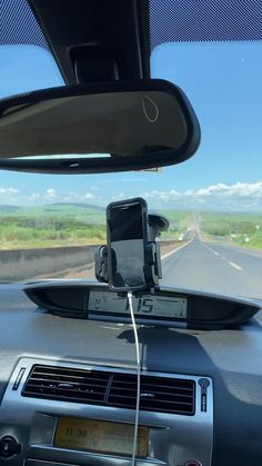 a car dashboard with a cell phone in the air and an electronic device attached to the dash board