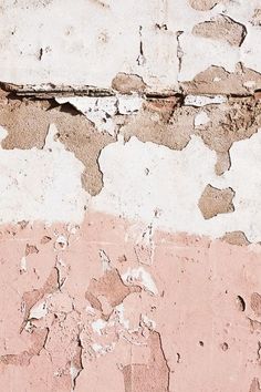 an old wall that has been painted pink and white with peeling paint on the side