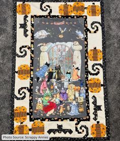 a quilted wall hanging with cats and pumpkins on it's sides, in front of a black background