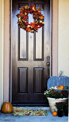 a front door decorated with fall leaves and pumpkins