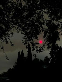 the sun is setting behind some trees on a cloudy day with dark clouds in the background