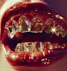 a woman's mouth with shiny, red lips and gold foil on the bottom