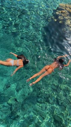 two women are swimming in clear blue water