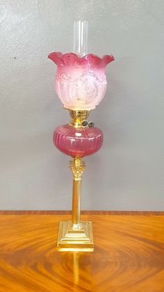 a pink glass vase sitting on top of a wooden table