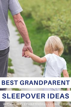 an older man holding the hand of a young child who is walking down a path