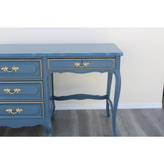 a blue desk with gold trim and drawers