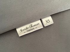 two tags that are on the side of a gray piece of furniture with words written on them