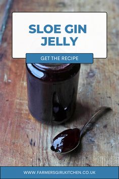 a jar of jelly sitting on top of a wooden table with a spoon next to it