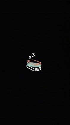 a laptop computer sitting on top of a table in the dark with hearts drawn on it