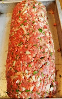 an uncooked meatloaf covered in sauce and herbs