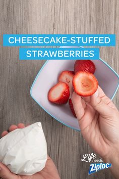 someone is holding up some strawberries in a white bowl on a wooden table with the words cheesecake - stuffed strawberries