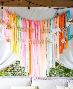 colorful streamers hanging from the ceiling in front of a white couch with pillows on it