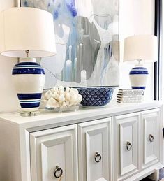 two blue and white vases sitting on top of a dresser next to a painting