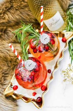 two glasses filled with drinks sitting on top of a tray next to christmas decorations and greenery