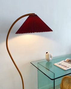 a lamp that is on top of a glass table next to a book and chair