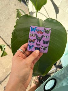 a person holding up a purple sticker with butterflies on it