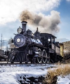 an old fashioned steam train traveling through the snow