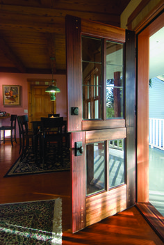 an open door leading to a dining room and patio area with wooden furniture on either side