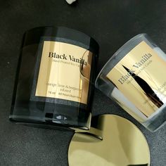 a black vanilla candle next to a gold heart shaped mirror