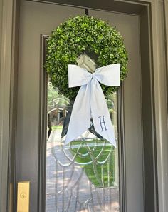 the front door is decorated with a wreath and monogrammed ribbon that says h