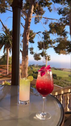 two drinks sitting on top of a table next to each other in front of a window