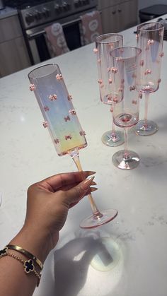 a hand holding a wine glass on top of a table next to several empty wine glasses