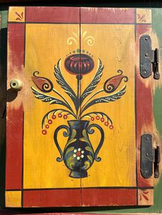 a painted wooden box with an ornate vase on it