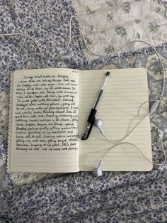 an open notebook with earbuds and headphones laying on a bed next to it