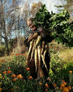 a woman is holding up some carrots in her hands