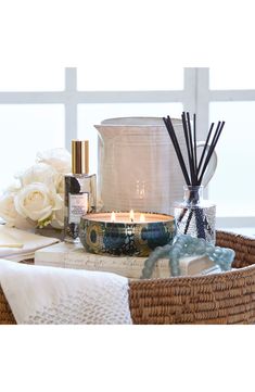 a basket filled with candles and flowers next to a vase on top of a table