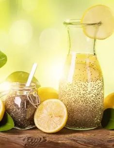 some lemons and other fruits are on a table with a glass pitcher filled with liquid