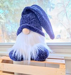 a blue and white stuffed gnome sitting on top of a wooden pallet next to a window