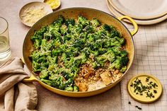 a pan filled with broccoli and rice on top of a table next to plates