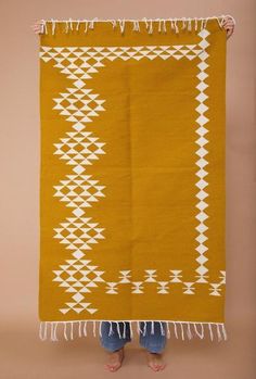 a woman standing in front of an orange and white rug with fringes on it