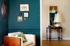 a living room with teal walls and pictures hanging on the wall, along with a white chair