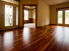 an empty living room with wood floors and french doors