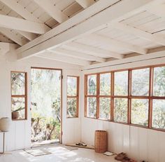 an empty room with large windows and wooden beams on the ceiling, in front of several pairs of shoes