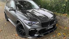 a grey bmw suv parked in front of a fence