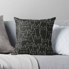 a black and white cat pattern on a gray couch with two pillows, one has a pillow