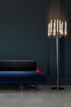 a blue couch sitting next to a tall light pole with five lights on top of it