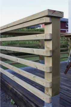 a wooden deck with metal railings next to a building and grass area in the background