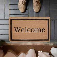 a welcome mat with the word welcome on it next to two pairs of brown shoes