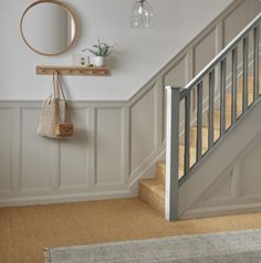 a hallway with white walls and beige carpeted flooring next to a wooden bannister