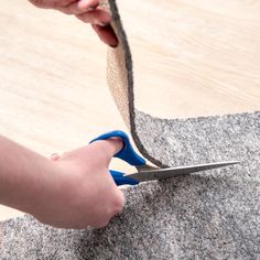 a person cutting fabric with scissors on top of a piece of felt that has been cut in half