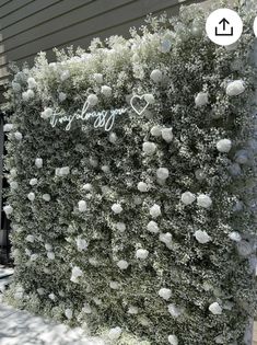 a wall with white flowers and the words happy new year written on it in front of a house