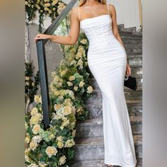 a woman in a white dress is standing on the stairs with her hand on her hip